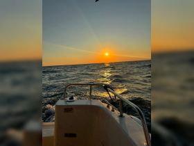 A serene sunset view from the bow of a boat, showcasing the tranquil waters and vibrant colors of the evening sky — perfect for romantic outings or peaceful cruises.