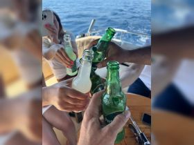 A lively group toasts with drinks aboard a boat, capturing the essence of celebration and camaraderie on the water.
