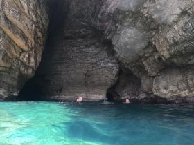 Swimmers explore a stunning cave surrounded by crystal-clear waters, showcasing the beauty of nature and adventure on the water.