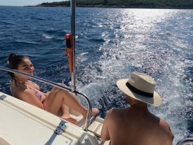 A couple enjoys a sunny day on the water, smiling and relaxing on a boat, capturing the essence of a perfect day at sea.