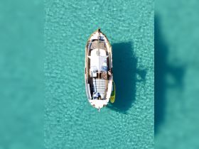 Aerial view of a boat anchored in stunning turquoise waters, showcasing a relaxing day on the water with guests enjoying the serene surroundings.