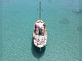 A group enjoys a relaxing day on a boat in crystal-clear waters, perfect for sunbathing and swimming — an ideal setting for a summer getaway.