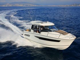 A sleek speedboat glides through the open water, showcasing its design and performance against a stunning coastal backdrop.