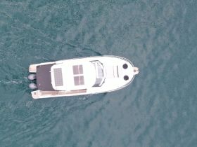 Aerial view of a sleek boat cruising through clear waters, showcasing its modern design and solar panels — perfect for eco-friendly boating adventures.