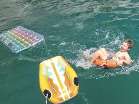 A joyful child splashes in the water while enjoying inflatable toys, capturing the essence of fun summer water activities.