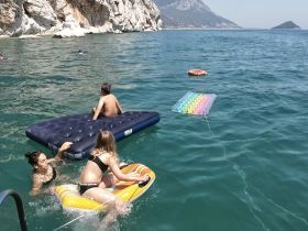 A fun-filled day at the beach with kids enjoying floating mats and swimming in clear waters — perfect for family adventures and summer outings.