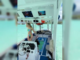 A vibrant interior view of a boat featuring a young woman standing at the helm, showcasing the comfortable seating and unique decor — perfect for a day out on the water.