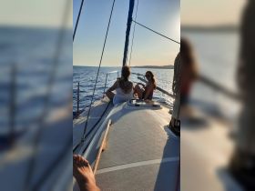 Two friends enjoy a serene sailing experience at sunset, capturing the essence of relaxation on the water.