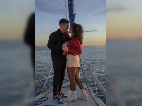 A couple shares a romantic moment on a sailboat at sunset, toasting with cocktails — an ideal setting for special celebrations or intimate outings on the water.