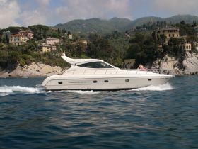 A sleek yacht cruises through clear waters, showcasing its elegant design against a picturesque coastal backdrop — perfect for luxury boating experiences.