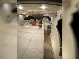 A cozy interior view of a boat's cabin featuring comfortable seating and a well-equipped helm, perfect for relaxing or entertaining while on the water.