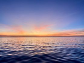 A stunning sunset over calm waters, creating a picturesque scene perfect for evening boat trips and relaxation on the water.