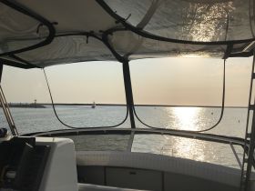 A serene view from the helm of a boat, showcasing the tranquil waters and sunset reflections — perfect for a peaceful day on the water.