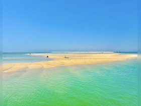 A picturesque sandbar scene with people enjoying the sun and water, perfect for a day of relaxation and fun in the beautiful turquoise waters.