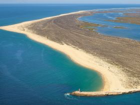 A stunning aerial view of a picturesque coastline and sandy beach, showcasing the natural beauty of the area — perfect for exploring by boat.