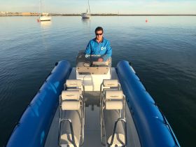 A view of the helm and seating area of a sleek boat, with a captain at the controls, showcasing the modern design and functionality ideal for a day on the water.