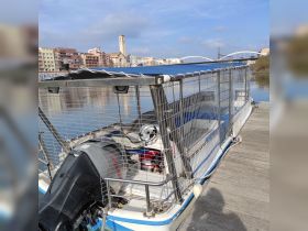 A detailed view of a boat docked at the waterfront, showcasing its structure and design against a scenic backdrop of the city.