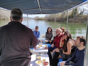 A group of guests enjoys a scenic boat trip while sharing food and engaging in conversation, creating a memorable experience on the water.