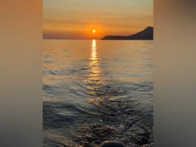 A serene sunset view over calm waters, showcasing the beautiful reflections and the silhouette of a distant coastline — perfect for tranquil evening boat rides.