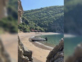 A scenic view of a boat anchored on a tranquil beach, surrounded by lush greenery — perfect for a relaxing getaway or beach day.