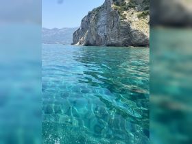 A stunning view of crystal-clear waters reflecting the rocky coastline, perfect for showcasing the natural beauty of the area.