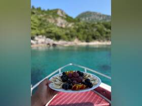 A vibrant fruit platter featuring bananas, grapes, and peaches, perfect for enjoying on a boat trip surrounded by stunning turquoise waters.