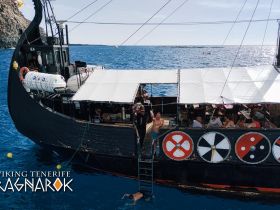 A lively group enjoys a day on the Viking Ragnarok boat, with guests swimming and socializing in the beautiful blue waters of Tenerife.