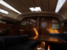 Interior view of a cozy boat cabin featuring a dining area and helm, perfect for relaxing during your nautical adventures.