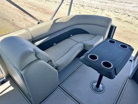 Interior view of a comfortable seating area on a boat, featuring plush cushions and a table with cup holders, perfect for relaxing while enjoying the water.