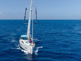 A vibrant sailboat navigates the deep blue waters, showcasing an exciting sailing experience on the open sea.