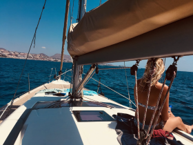 A woman relaxes on the deck of a sailboat, enjoying the ocean views and the sun — a perfect moment for sailing enthusiasts.