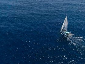 Aerial view of a sailboat gracefully navigating through deep blue waters, showcasing the beauty of sailing adventures.