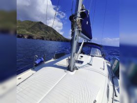 A stunning view of a sailboat navigating through clear waters, with lush green hills in the background — perfect for sailing enthusiasts and adventure seekers.