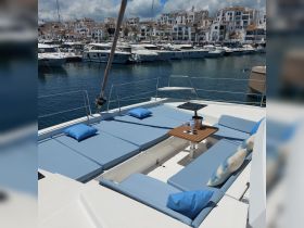 A spacious lounge area on a yacht featuring comfortable seating and a table, perfect for relaxing and enjoying the marina views.