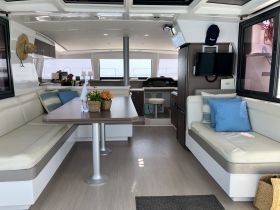A spacious and modern interior of a boat featuring comfortable seating and a dining area, perfect for relaxing and enjoying meals while at sea.