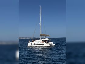 A lively catamaran sails through the clear waters, with guests enjoying the sun and sea — perfect for group outings and adventures on the water.