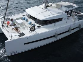 Two guests relax on the deck of a luxurious Bali catamaran, enjoying the sun and sea — an ideal setting for a day of leisure on the water.