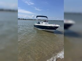 A sleek speedboat anchored in shallow waters, showcasing its elegant design against a backdrop of clear blue skies and distant shoreline.