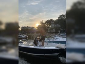 A man cleans his boat at sunset, creating a picturesque scene at the dock — perfect for evening outings and water adventures.