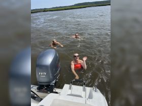 A group of friends enjoys a refreshing swim in the water, with one waving cheerfully from the surface — perfect for summer fun on the water.