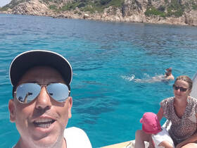 A joyful family enjoys a day on the water, with one member snorkeling and others relaxing on the boat — a perfect snapshot of summer fun in crystal-clear waters.