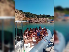 A lively group of friends enjoys cocktails aboard a boat, soaking up the sun and celebrating their day at the beach — perfect for summer outings and memorable gatherings.