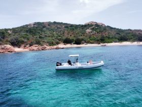 A couple enjoys a relaxing moment on a boat near a picturesque island, surrounded by crystal-clear waters — perfect for a day of exploration and adventure.