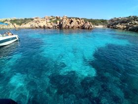 A scenic view of a boat anchored in crystal-clear waters, surrounded by stunning rock formations — a perfect spot for exploring the coastline.