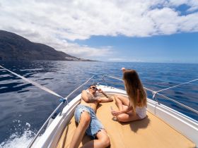 A couple enjoys a relaxing day on a boat, soaking up the sun and the stunning ocean views — perfect for romantic getaways or leisurely outings.