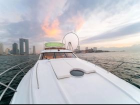 A stunning view of a yacht cruising in the water, showcasing the skyline and a ferris wheel in the background — perfect for luxury boating experiences.
