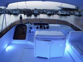 A well-lit interior view of a boat's helm and cabin area, showcasing the modern console and seating, perfect for comfortable navigation and relaxation.