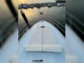 A serene view from the bow of a yacht, showcasing comfortable seating and a beautiful sunset over the marina — perfect for relaxation and enjoying the water.