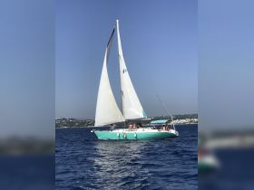 A lively group enjoys a sailing adventure on a beautiful day, showcasing the joy of being on the water aboard a vibrant sailboat.