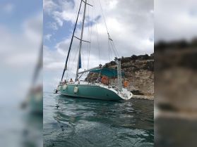 A sailboat navigates calm waters with guests on board, showcasing a perfect day for sailing and exploration along the scenic coastline.
